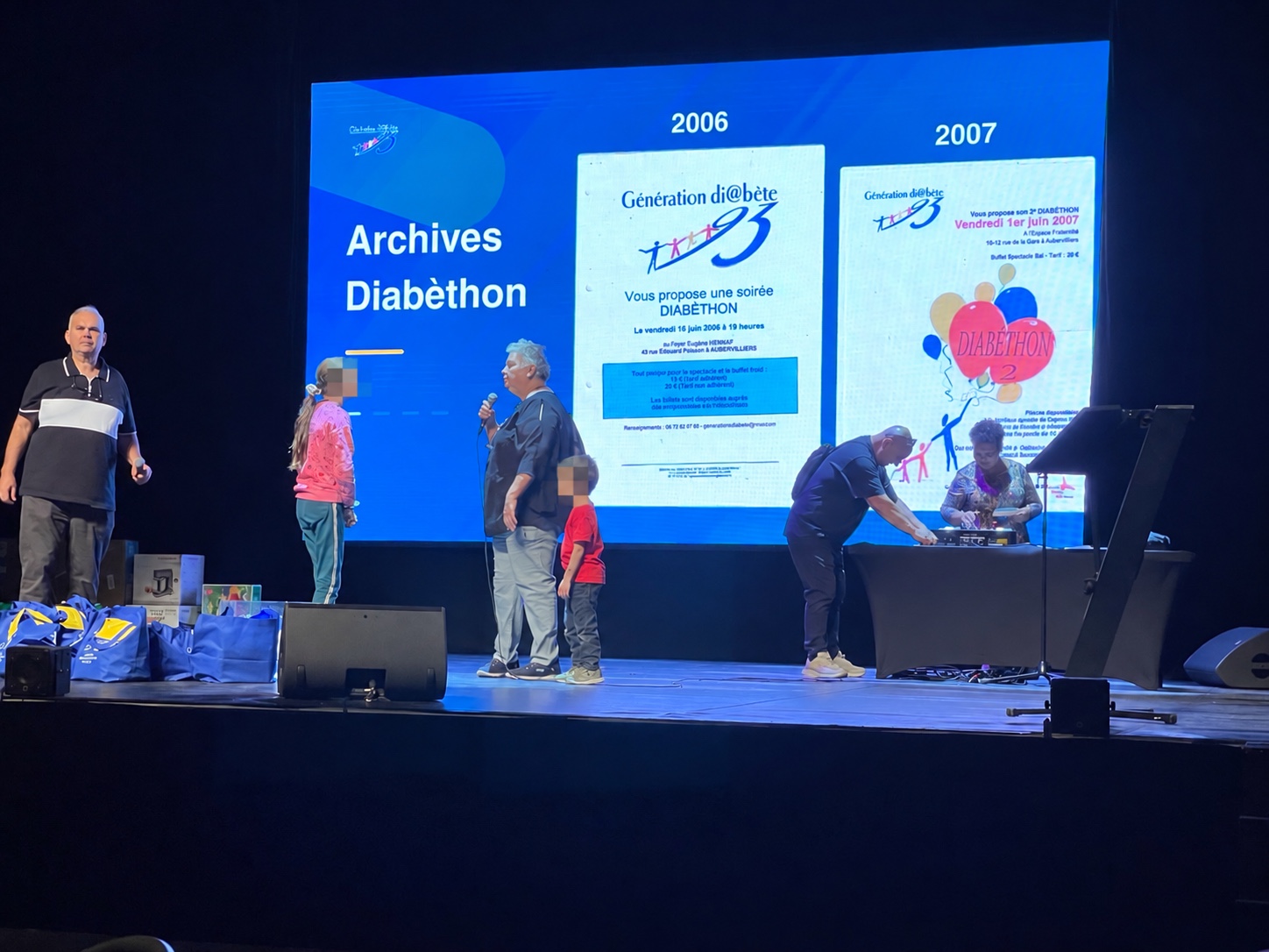 Animation sur scène devant les affiches d’archives du Diabéthon. Les visages des deux enfants sont masqués.